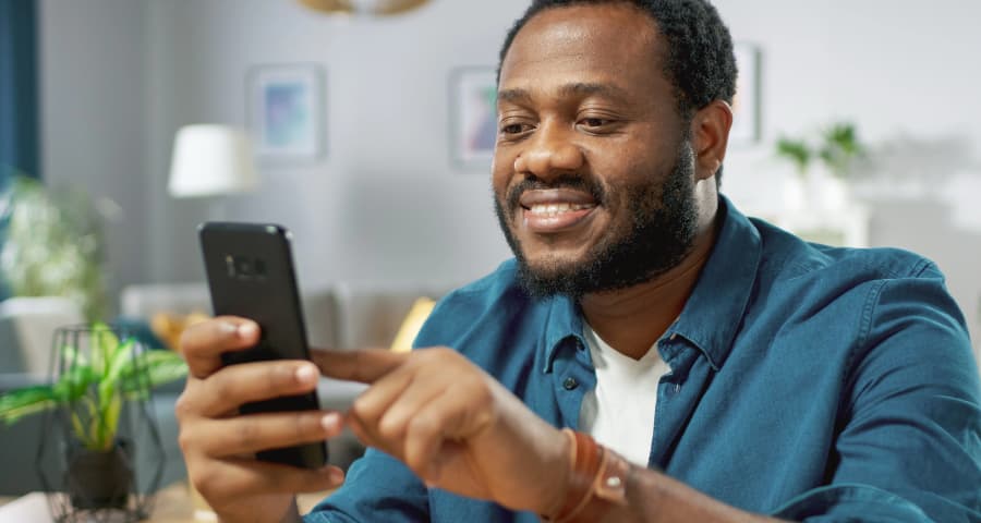 Man at home interacting with an app on his phone
